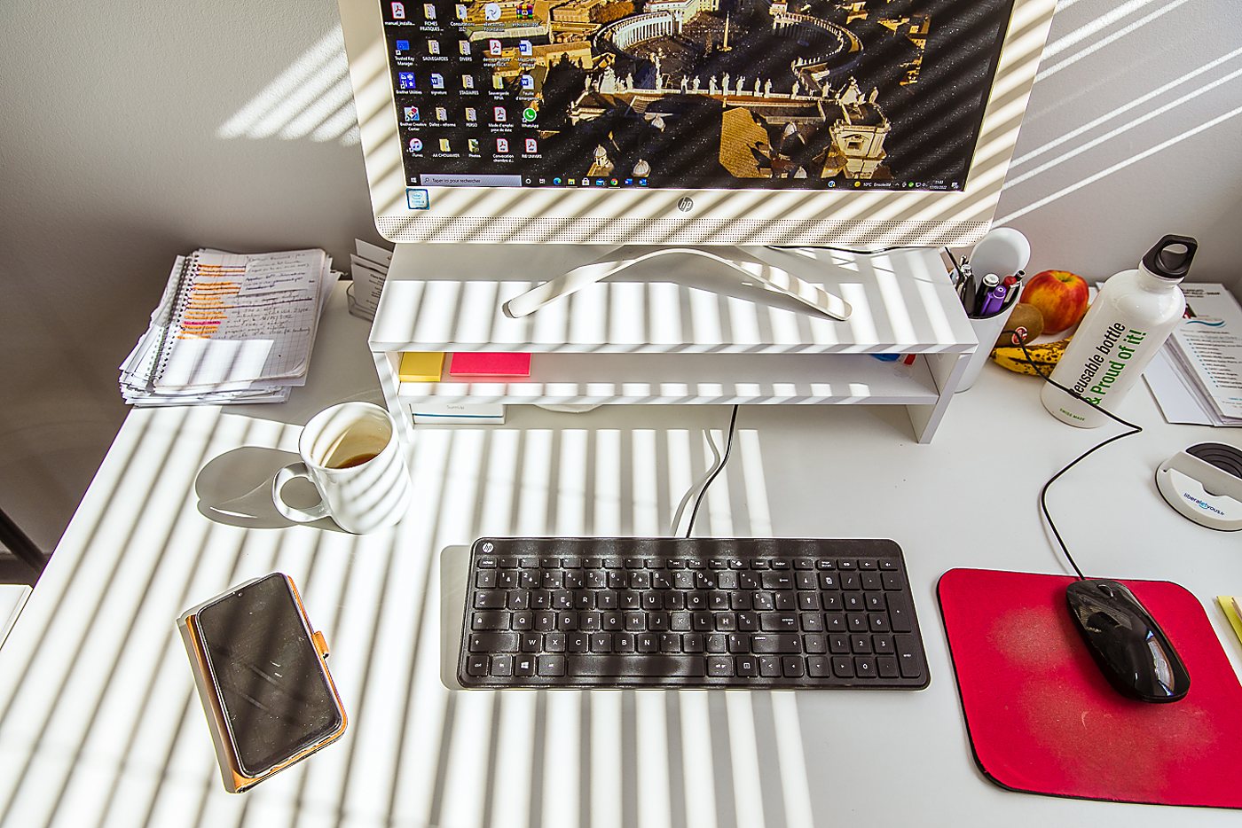 Bureau blanc ensoleillé avec ordinateur et tasse de café.