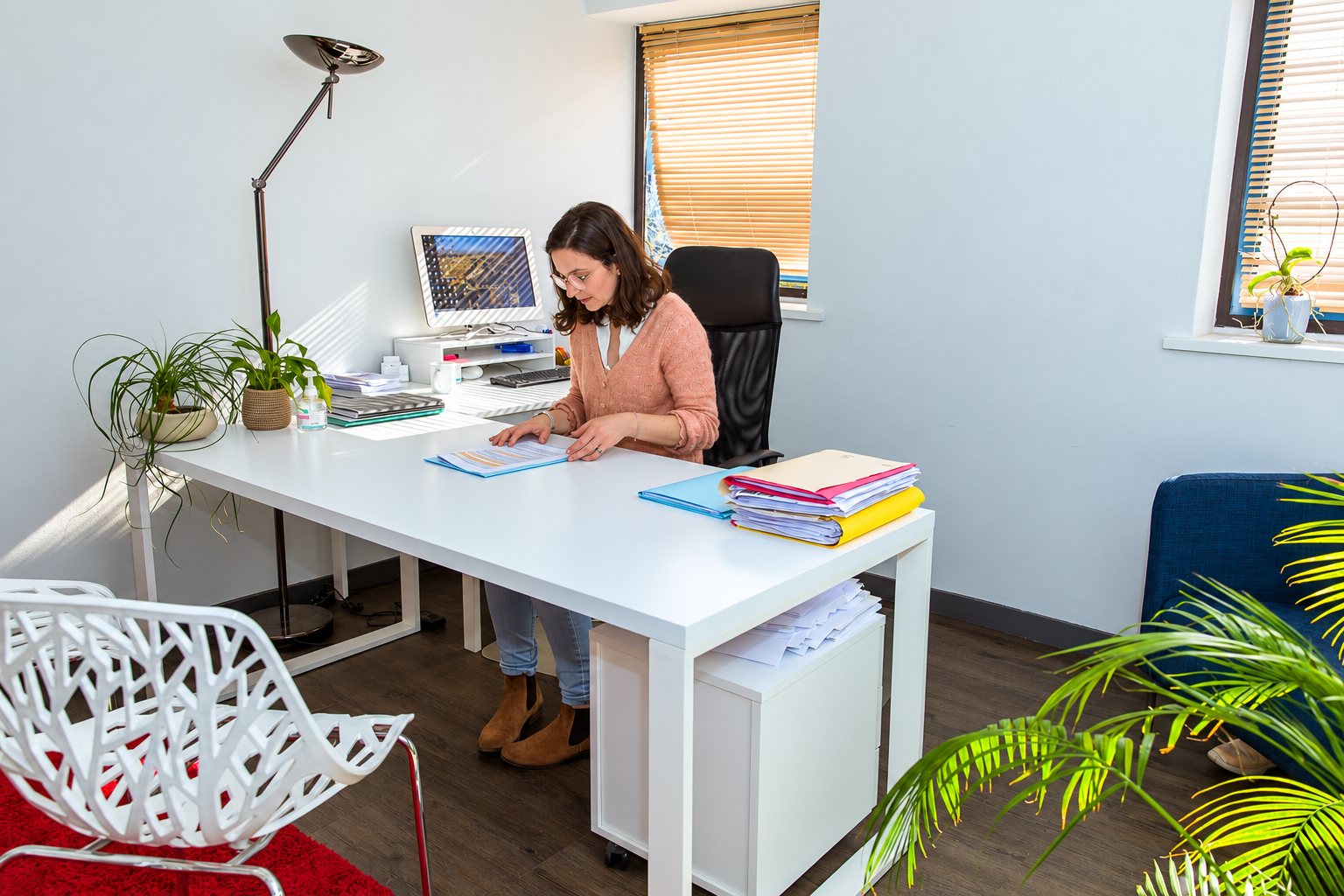Femme travaillant sur des dossiers dans un bureau lumineux.