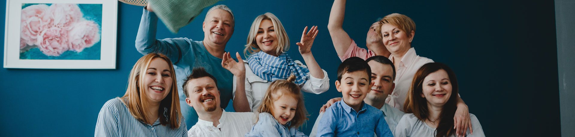Grande famille joyeuse posant devant un mur bleu.